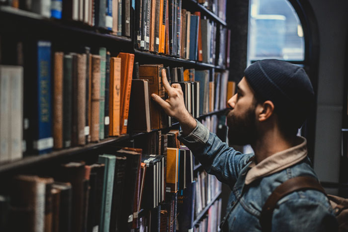 Man browsing books at library shelves