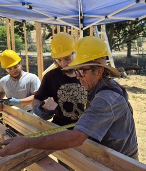 Three students measuring lumber