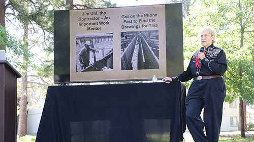 Dr. Temple Grandin standing next to slide presentation on display monitor.