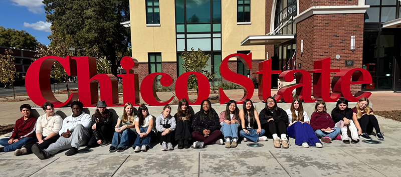 Students sitting in front of Chico State sign